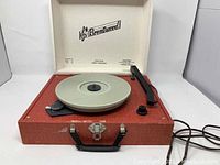 Full view of Brentwood record player with reddish textured carrying case open, showing turntable, tonearm, and control knob.
