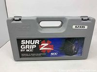 Gray hard plastic carrying case labeled 'SHUR GRIP by SCC' with model number SZ335 sticker visible, showing branding and design claims.