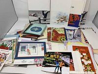 Wide view of assorted vintage Christmas cards including envelopes in various designs and sizes spread out on white background.