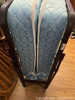 Photo of the vintage fold down single bed folded vertically, showing the patterned blue mattress and metal frame sides.