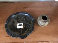 View of large pottery bowl with dark glaze and organic edge, and small round pottery bowl with light surface