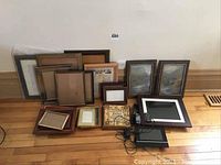 Wide view of all frames arranged on floor, showing size variety and contents including prints and digital frames