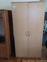 Full view of the closed pressboard cabinet showing two doors and handles.