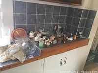 Photo showing wide view of decor items on countertop including crystal, figurines, doilies, and other glassware.