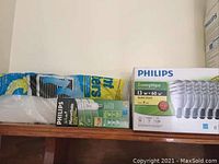 Boxes of Philips light bulbs on shelf including 13W 60W equivalent soft white bulbs and others
