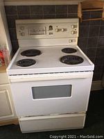 White Moffat electric stove with four coil burners and oven door with window, showing overall stove design and size