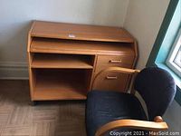 Desk positioned near the wall showing top, storage compartments, drawer, and castors along bottom edges. Visible wear and peeling edging noted.