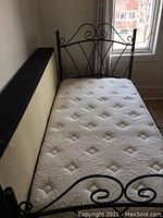 Full side view of metal bed frame with mattress showing beige boxspring and mattress details