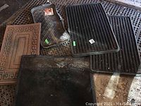 Overview of five rubber and vinyl mats of various sizes and patterns on a garage floor