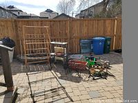 Full view of garden items grouped outside, including metal and wooden stands, flower pots, solar lights, and plastic items.