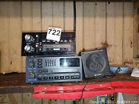 Two car stereos and one Cobra noise canceling speaker on a shelf. The stereos have tape decks, one labeled Delco with auto reverse function, the other with built-in equalizer sliders. Speaker cable visible.