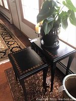 Two black nesting tables stacked, showing geometric square inlay design on top surfaces and angled legs.
