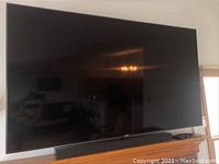 Front view of the 75" screen on a wooden credenza with screen off.
