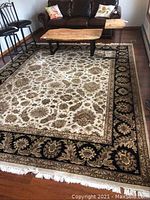 Wool carpet laid flat in a living room under coffee tables and chairs, showcasing full pattern and fringe.