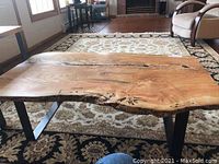 Full view of live edge slab coffee table showing top and metal legs.