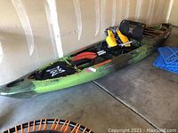 Overall view of green camouflage kayak with seat and accessories