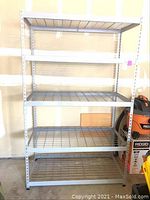 Front view of entire five tier metal storage shelf showing spacing and grid shelf structure.