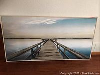 Full view of seascape painting leaning against wall on hardwood floor