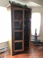 Full front view of the wooden wine cellar cabinet showing one door slightly open to reveal interior shelves and wine rack compartments.