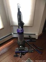 Main vacuum unit and accessories arranged on hardwood floor near window