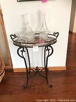 Full view of metal and glass tray table with two crystal decanters and four glasses arranged on top, showing table design and floor placement.