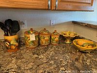 Photo of three graduated Mexican ceramic canisters signed Mavolich and two fruit bowls on granite countertop