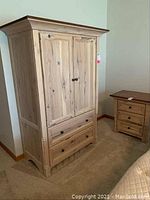 Front view of the hickory wood armoire showing two doors and two drawers with black knobs, light natural wood finish.
