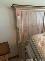 Close-up of the left side of the headboard showing the vertical paneling, turned post and crown molding with a small label attached.