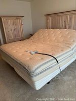 King size Sleep Number electric adjustable bed frame with mattress and remote control on top, showing the entire bed setup.