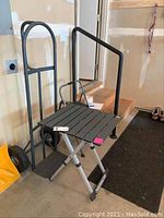 Photo showing Werner two-step folding step stool, Milwaukee hand truck, and GCI Outdoor folding camp table together in garage area.