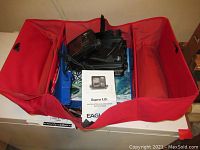 Red carrying case open with Supra ID fishfinder, cables, transducer, and instruction manual inside.