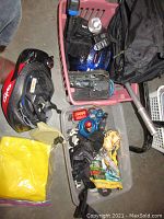Top-down view of crate and a tub filled with various cycling equipment including helmets, gloves, locks, tools, lights, and rain poncho