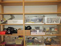 Wide shot of shelves with multiple plastic bins and boxes containing various hardware, cables, and electrical items.