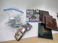 Photo showing various collectible card game cards in plastic bags along with three different card binders/notebooks.