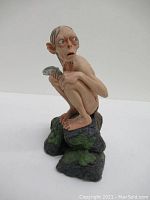 Front-left angled view of the Smeagol statue revealing facial details, crouching pose, and fish in hand.