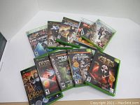 Photo of 10 Xbox and Xbox 360 game cases with cover art arranged on white surface.
