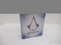 Assassin's Creed box art showing the logo on a white/blue gradient background.