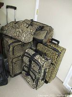 Full view of the set of five leopard print luggage pieces grouped together against a wall, showing a mix of sizes including soft carry bag and wheeled suitcases.
