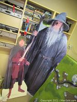 Full view of both life size cardboard cutouts, Gandalf and Frodo, displayed indoors