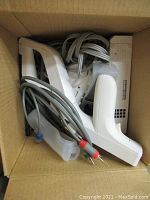Box containing Nintendo Wii console, controllers, sensor bar, power adapter, and AV cables.