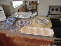 Full view of assorted ceramic serving dishes and coasters arranged on kitchen counter.