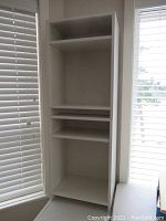 Full view of tall white MDF shelf unit with adjustable shelves showing structure and condition.