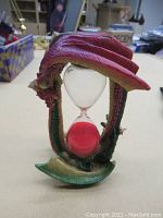Front view showing the dragon shaped frame and red sand hourglass inside.