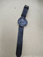 Full view of Marc Ecko watch with black rubber strap laid flat.