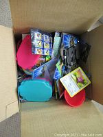 View into the box showing assorted items including Pokemon cards, a pink pouch, and a blue/red plastic container.