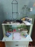 Photo of a room corner with multiple items including metal racks, Canon Selphy CP800 photo printer, various stationery and supplies on a green desk with shelves.