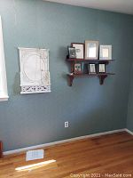 Wide view of two wooden shelves mounted on wall holding seven picture frames