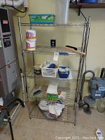 Full view of the 5-shelf metal wire rack and contents including paper towels, brush, bins, and other items.