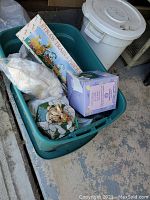 Photo of tub filled with various Easter decorations, including boxes, tissue, and other decor items inside a green storage container.