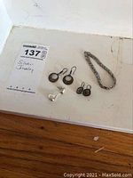Four pieces of sterling silver jewelry including 2 sets of earrings, one single earring, and a bracelet displayed on a white surface.